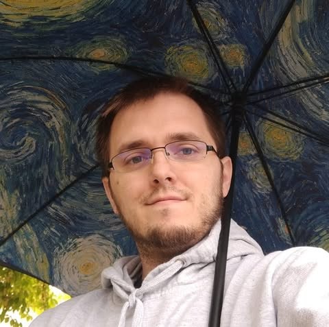 Randy, in glasses and a gray hoodie, under an umbrella printed with a swirling starry night